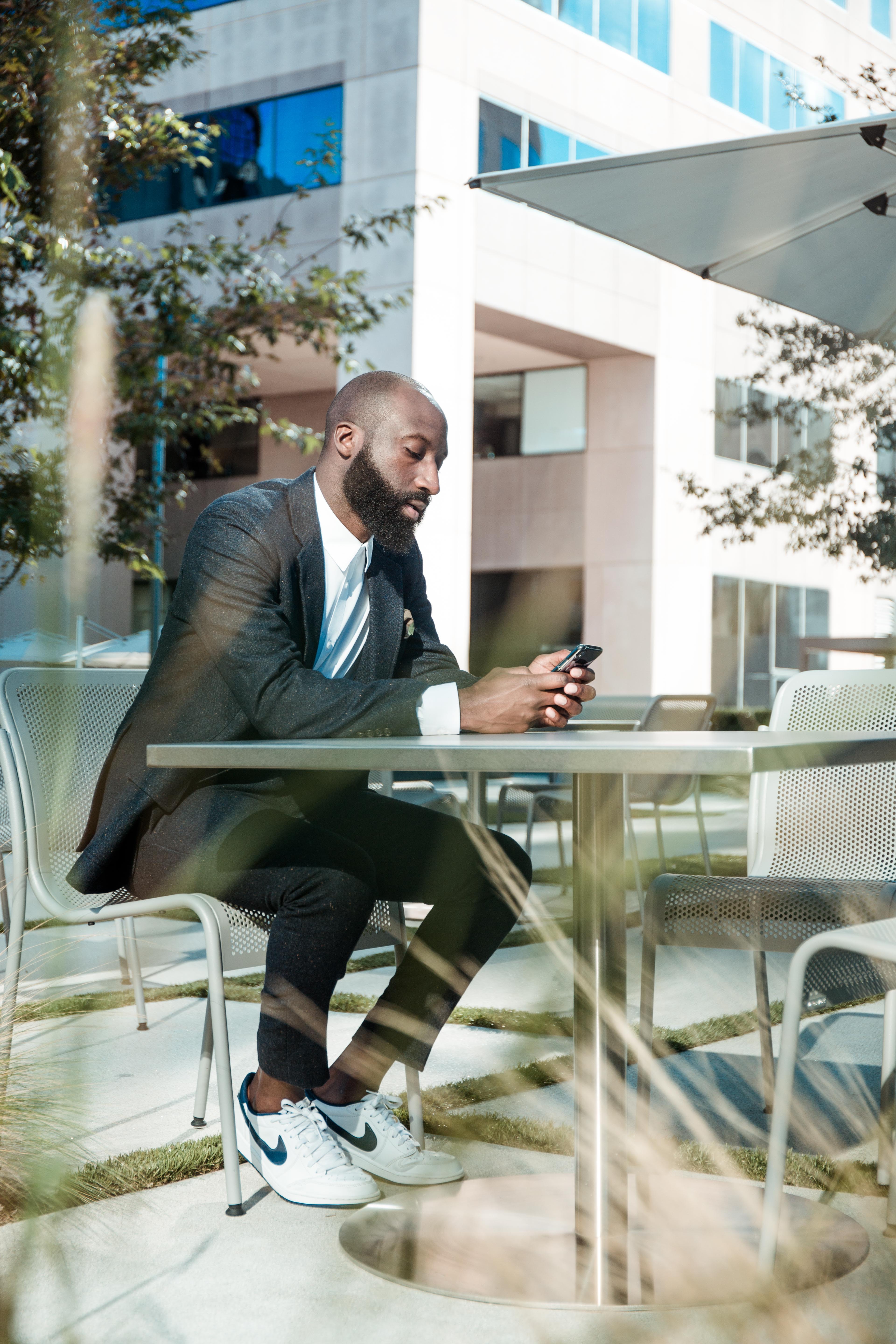 Man sitting at a table holding and looking at a smartphone